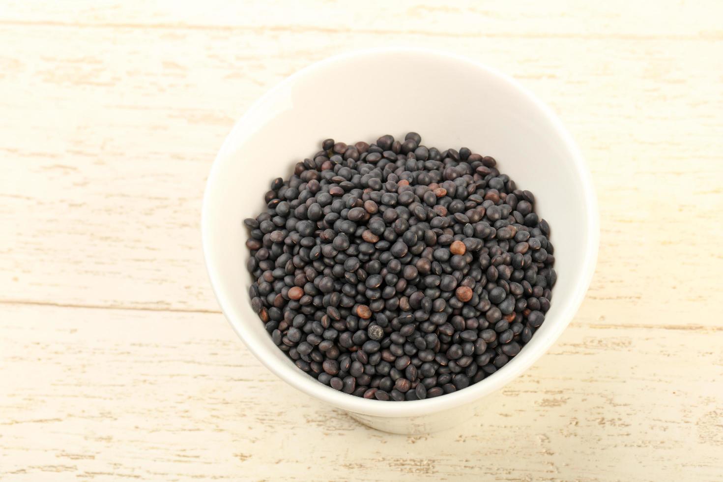 Black lentils in a bowl on wooden background photo
