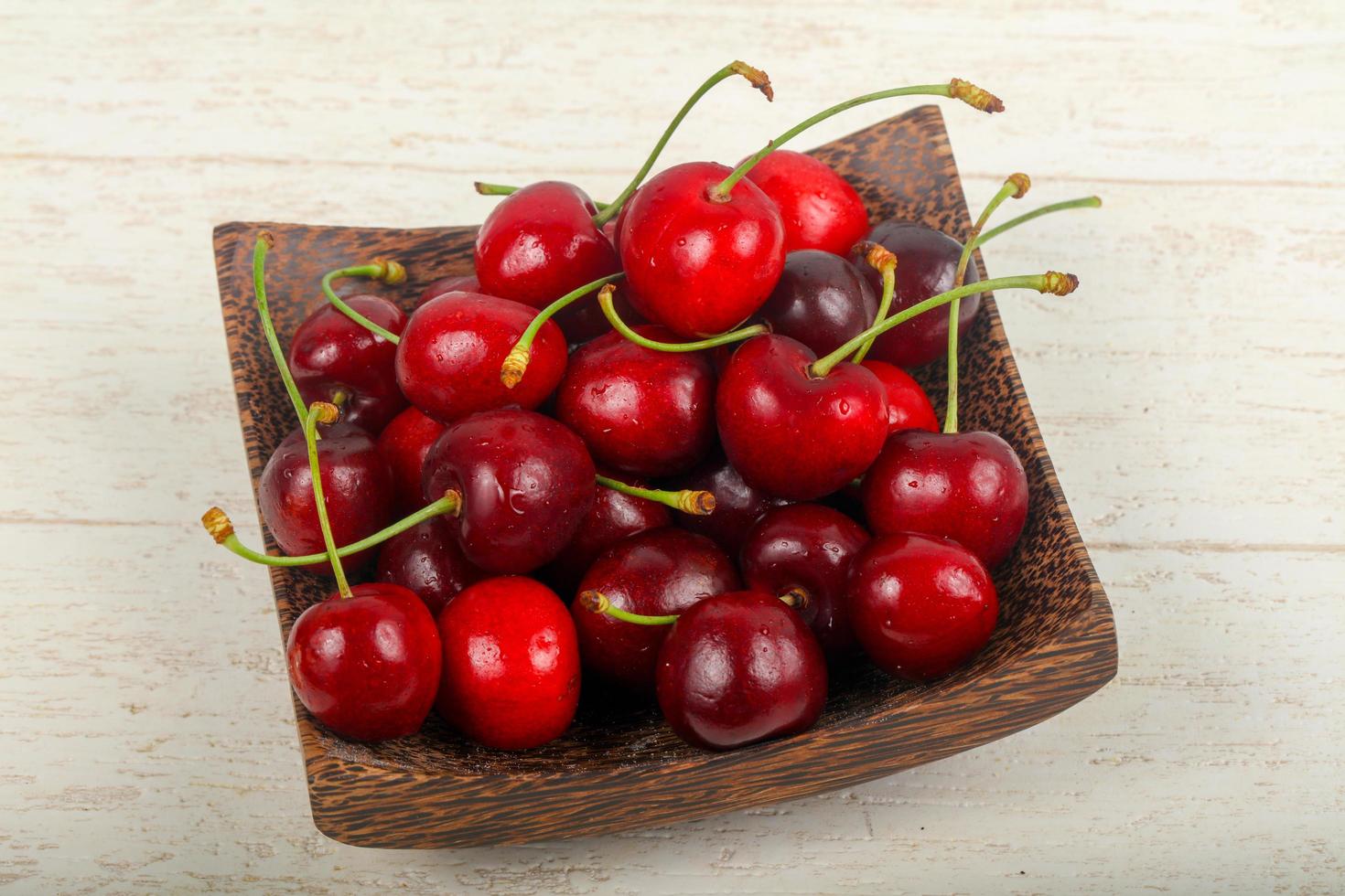Sweet cherry on the plate and wooden background photo