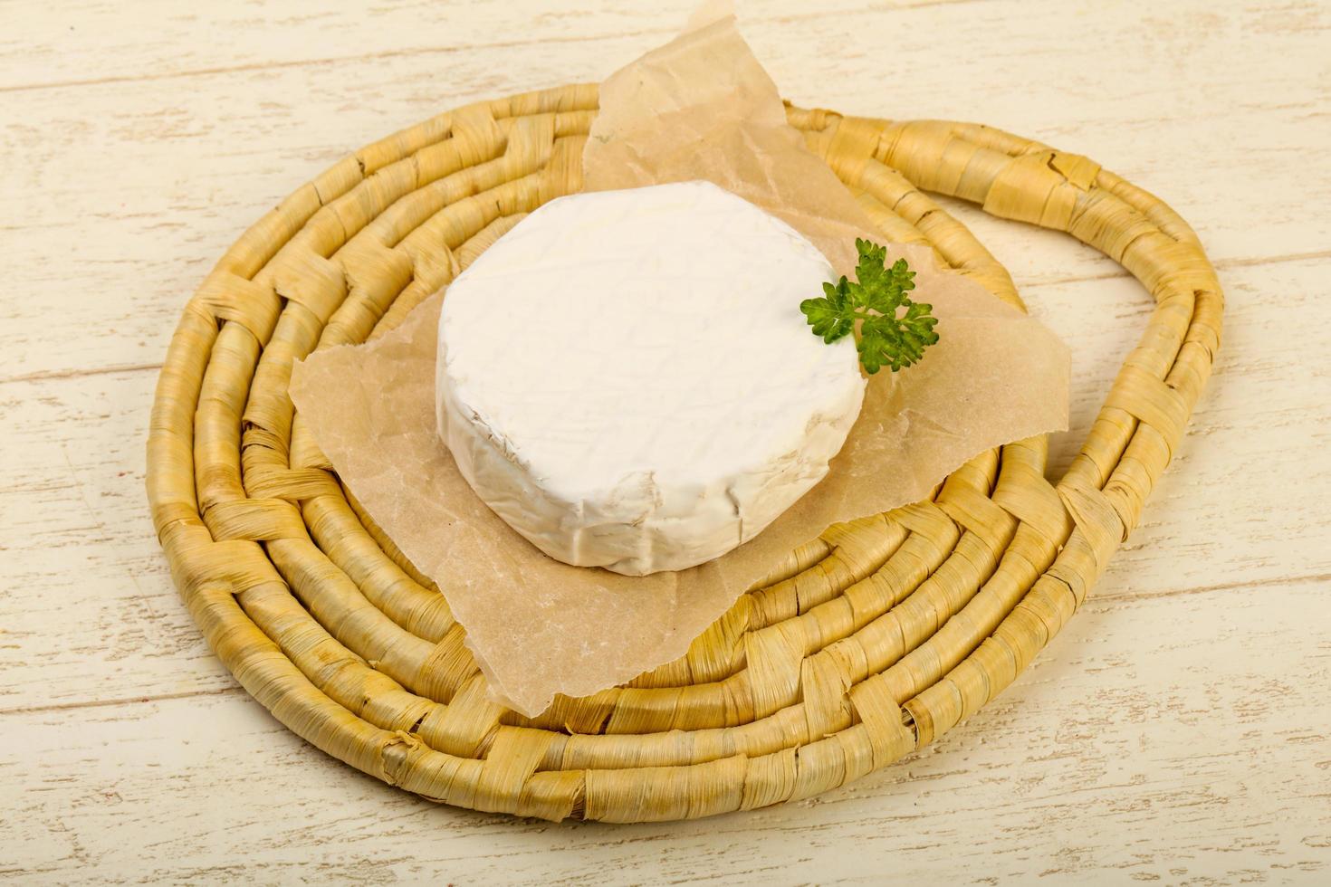 queso camembert sobre tabla de madera y fondo de madera foto