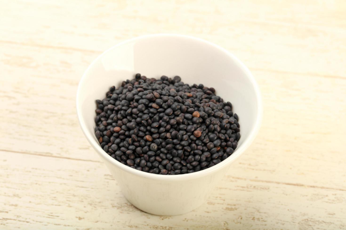 Black lentils in a bowl on wooden background photo
