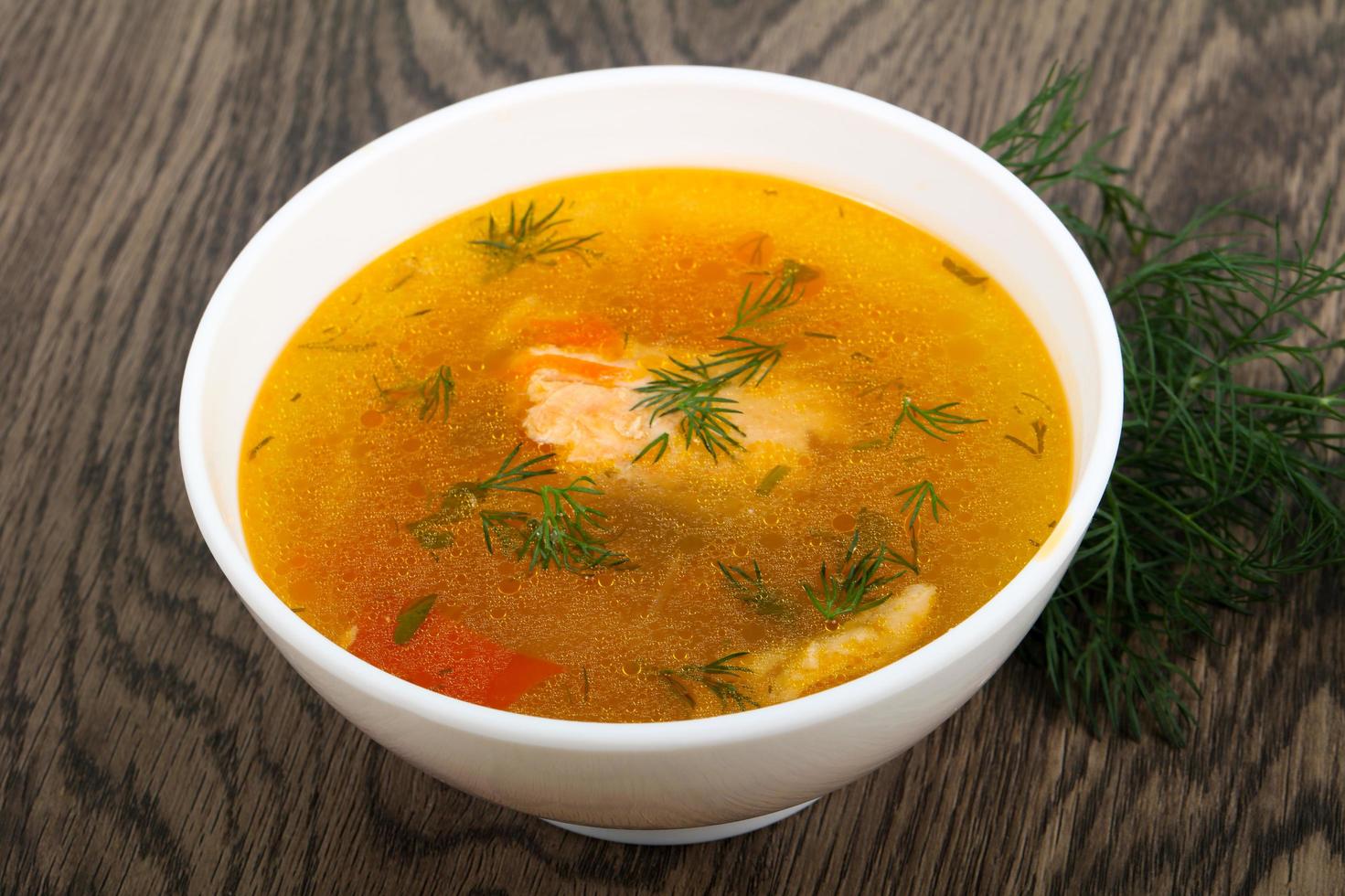 Salmon soup in a bowl on wooden background photo