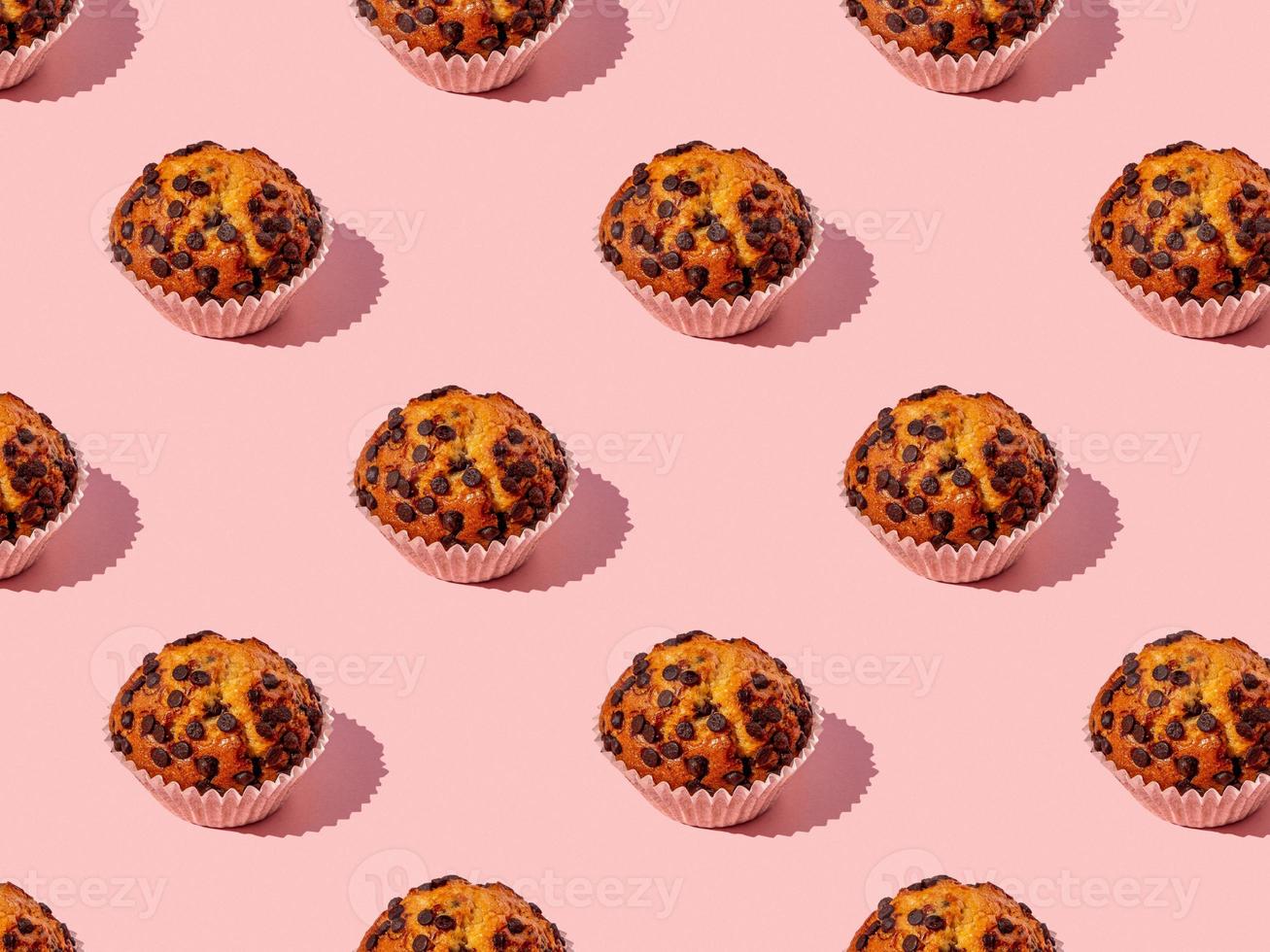 top shot seamless pattern of a yummy chocolate chips cupcake on a pink background photo