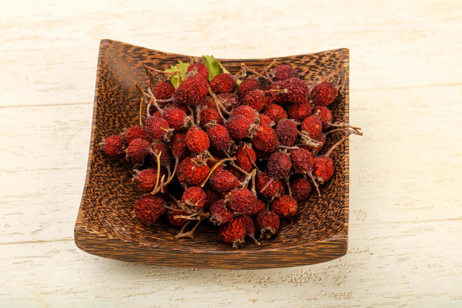 Dry hawthorn in a bowl on wooden background photo