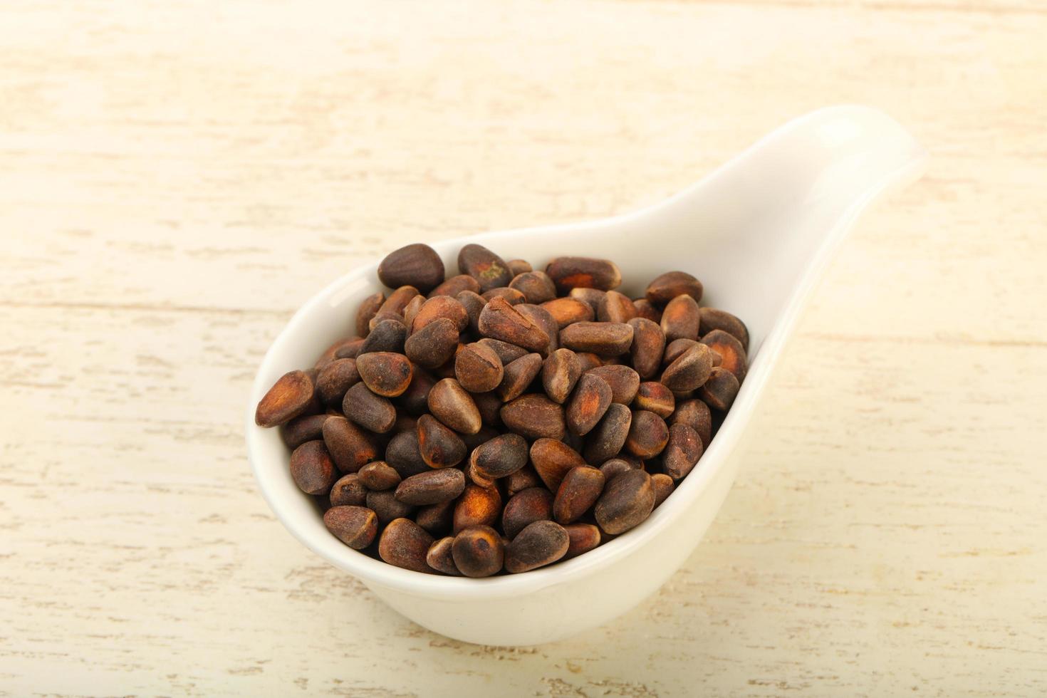 Cedar nuts in a bowl on wooden background photo