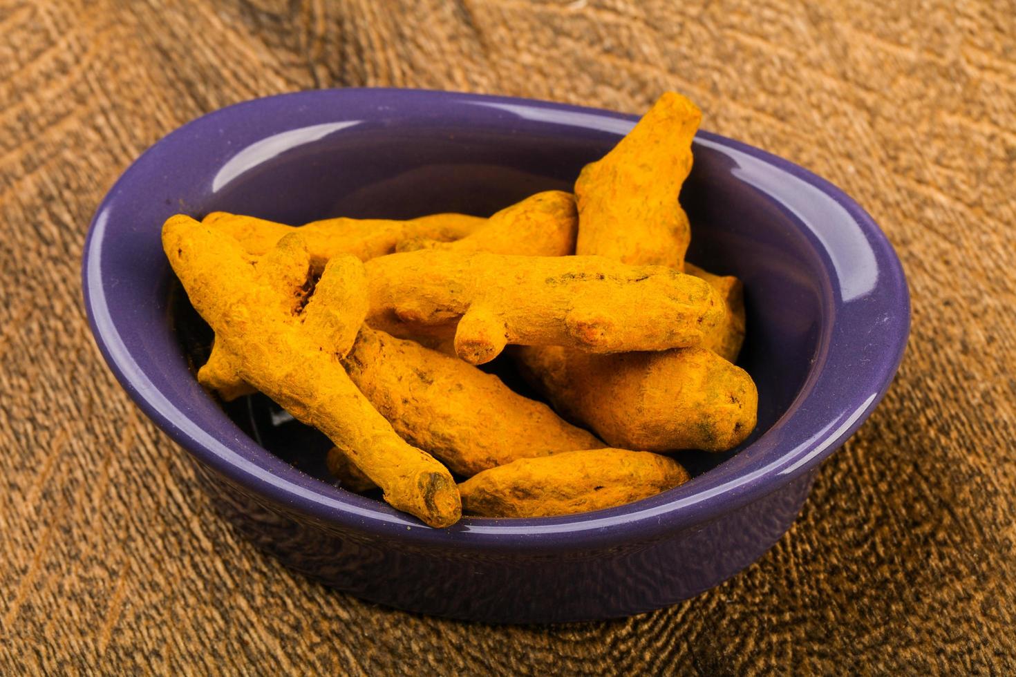 Tumeric roots in a bowl on wooden background photo