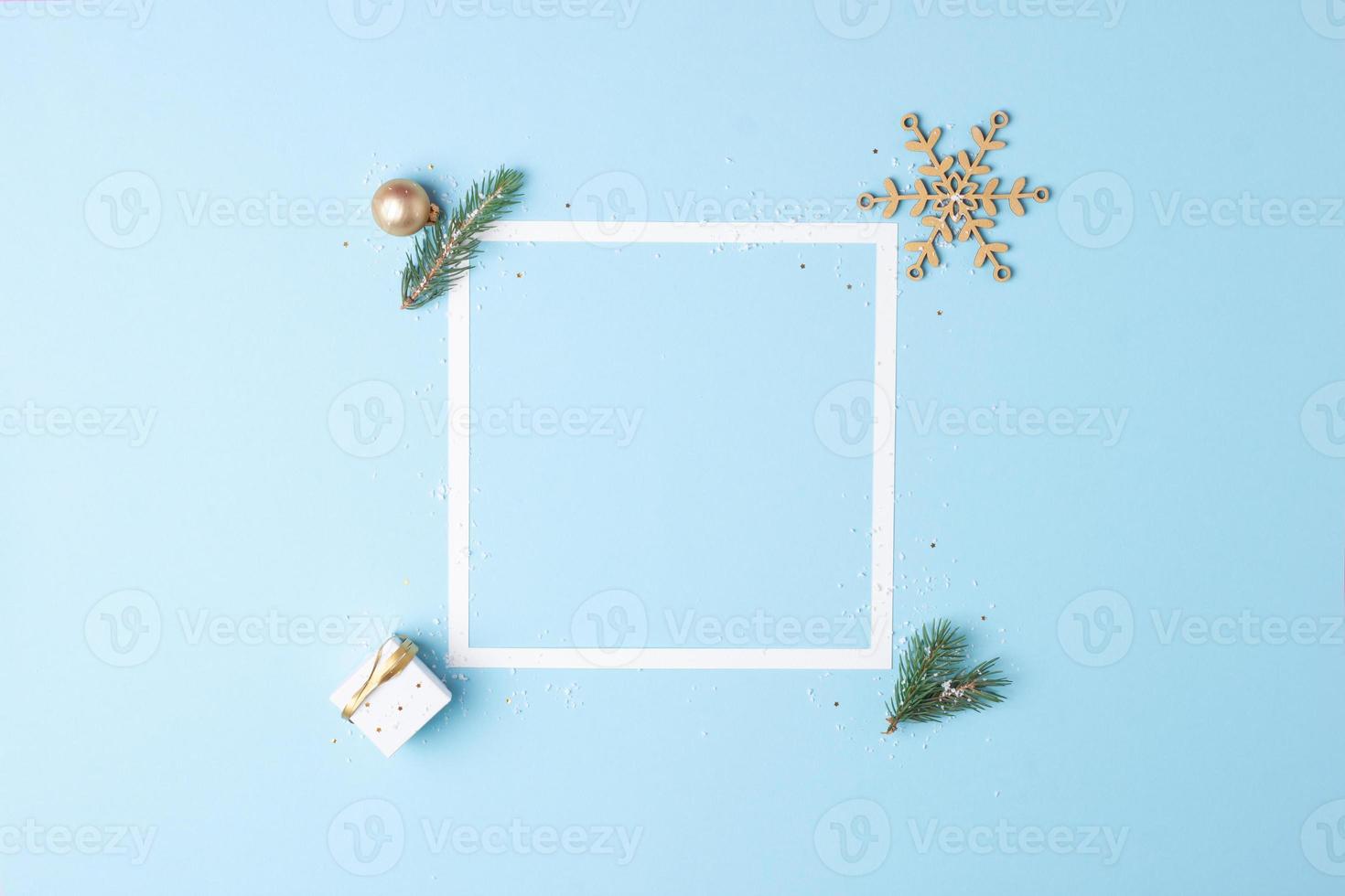 Christmas decorations with white frame and gift on blue background. Flat lay, copy space photo