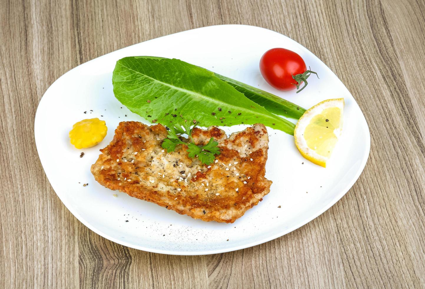Pork schnitzel on the plate and wooden background photo