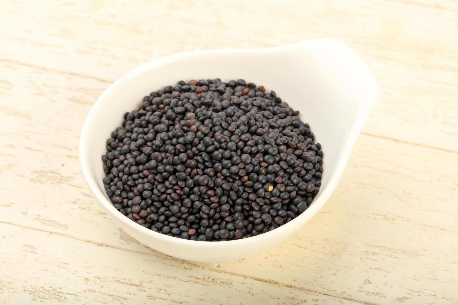 Black lentils in a bowl on wooden background photo
