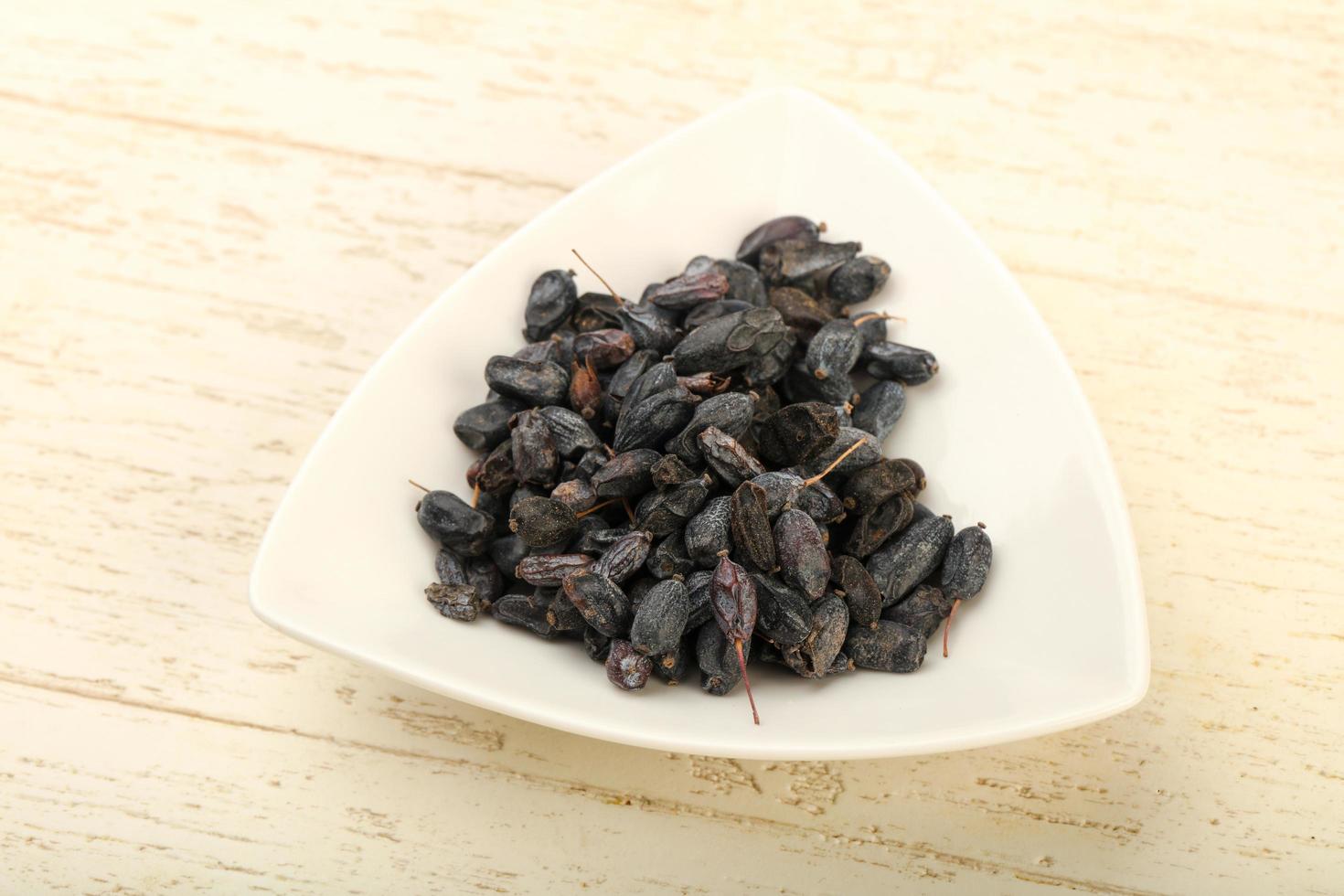 Dry barberry in a bowl on wooden background photo