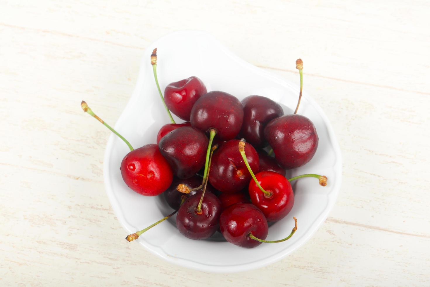 Sweet cherry in a bowl on wooden background photo