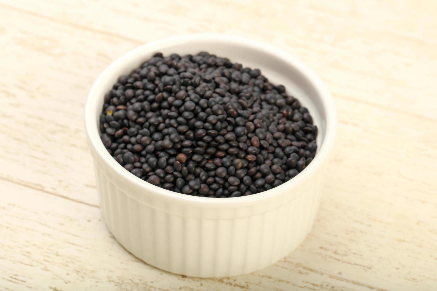 Black lentils in a bowl on wooden background photo