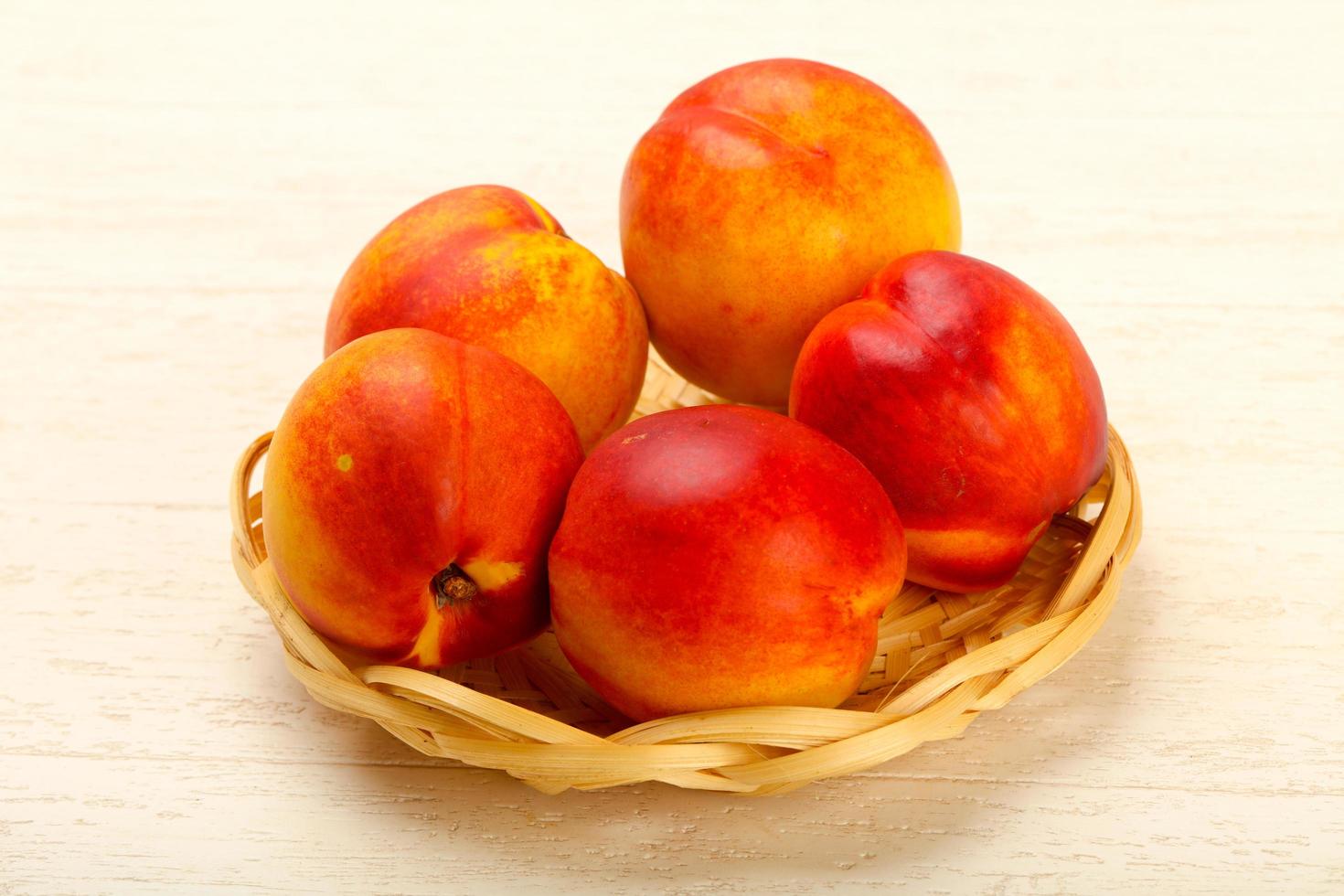 Nectarines in a basket on wooden background photo