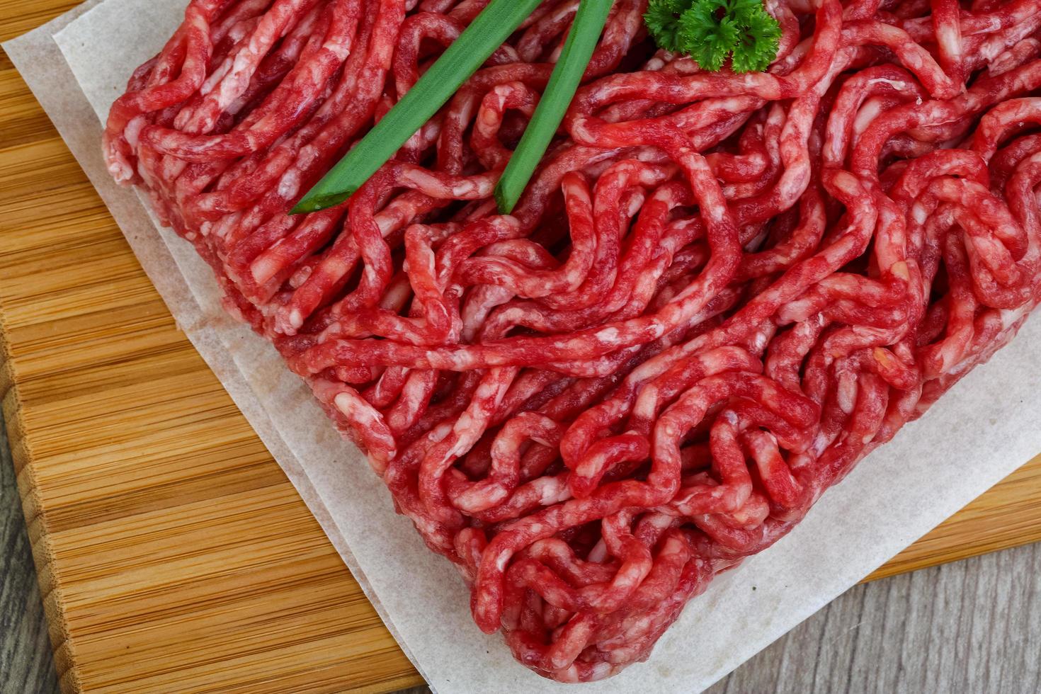 Minced beef on wooden board close up view photo