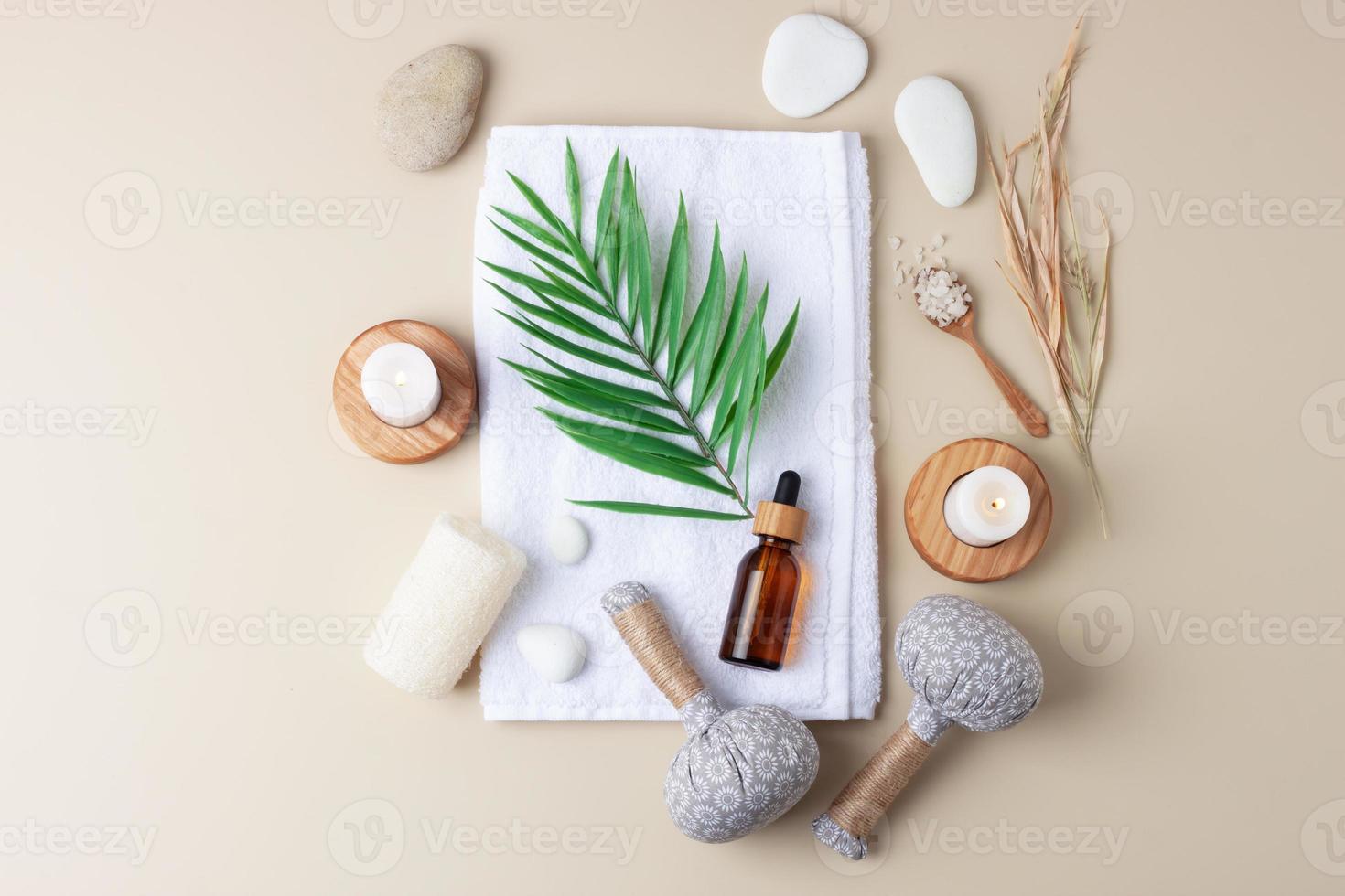 tratamiento de spa con botella cosmética, velas y bolsa de hierbas, toalla sobre fondo beige. endecha plana foto