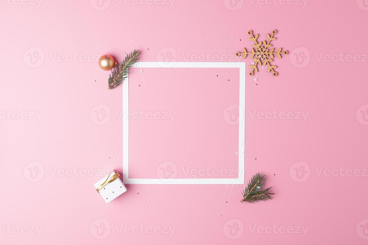 Christmas decorations with white frame and gift on pink background. Flat lay, copy space photo