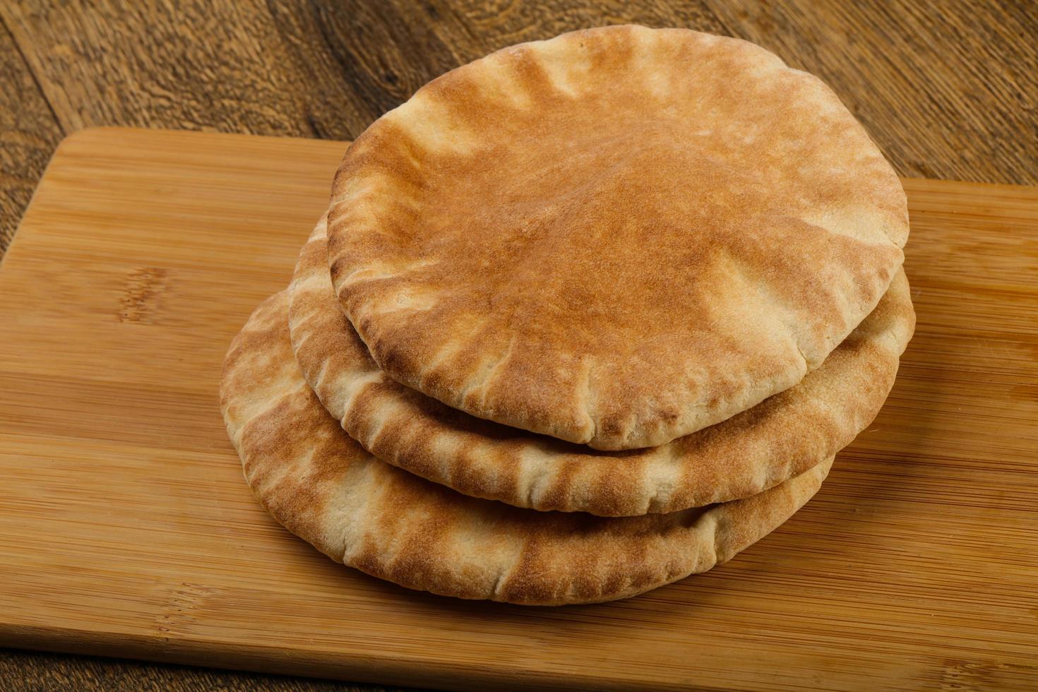 Pita bread on wooden board and wooden background photo