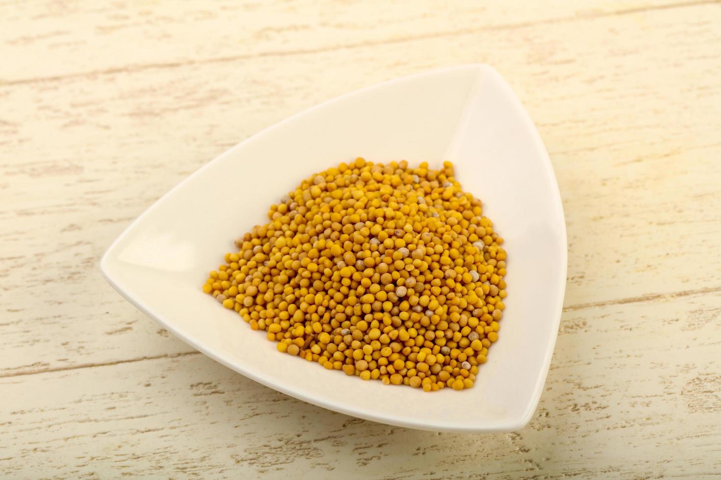 Mustard seeds in a bowl on wooden background photo