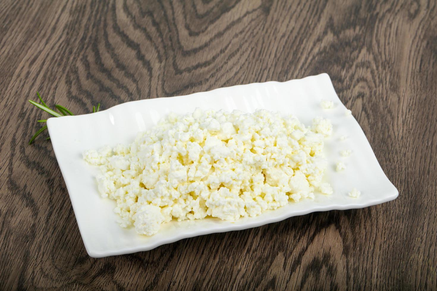 Cottage cheese on the plate and wooden background photo