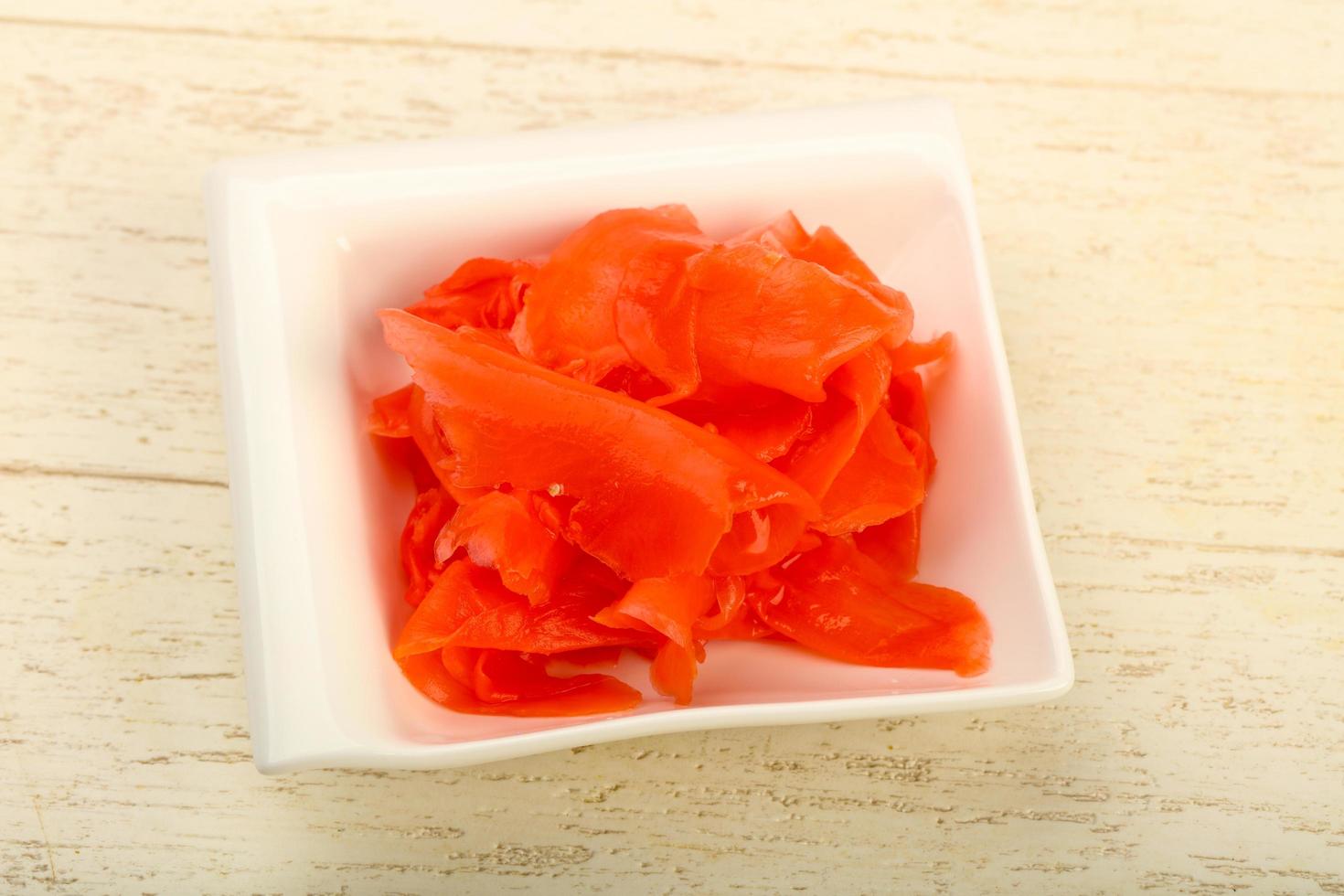 Picked ginger in a bowl on wooden background photo