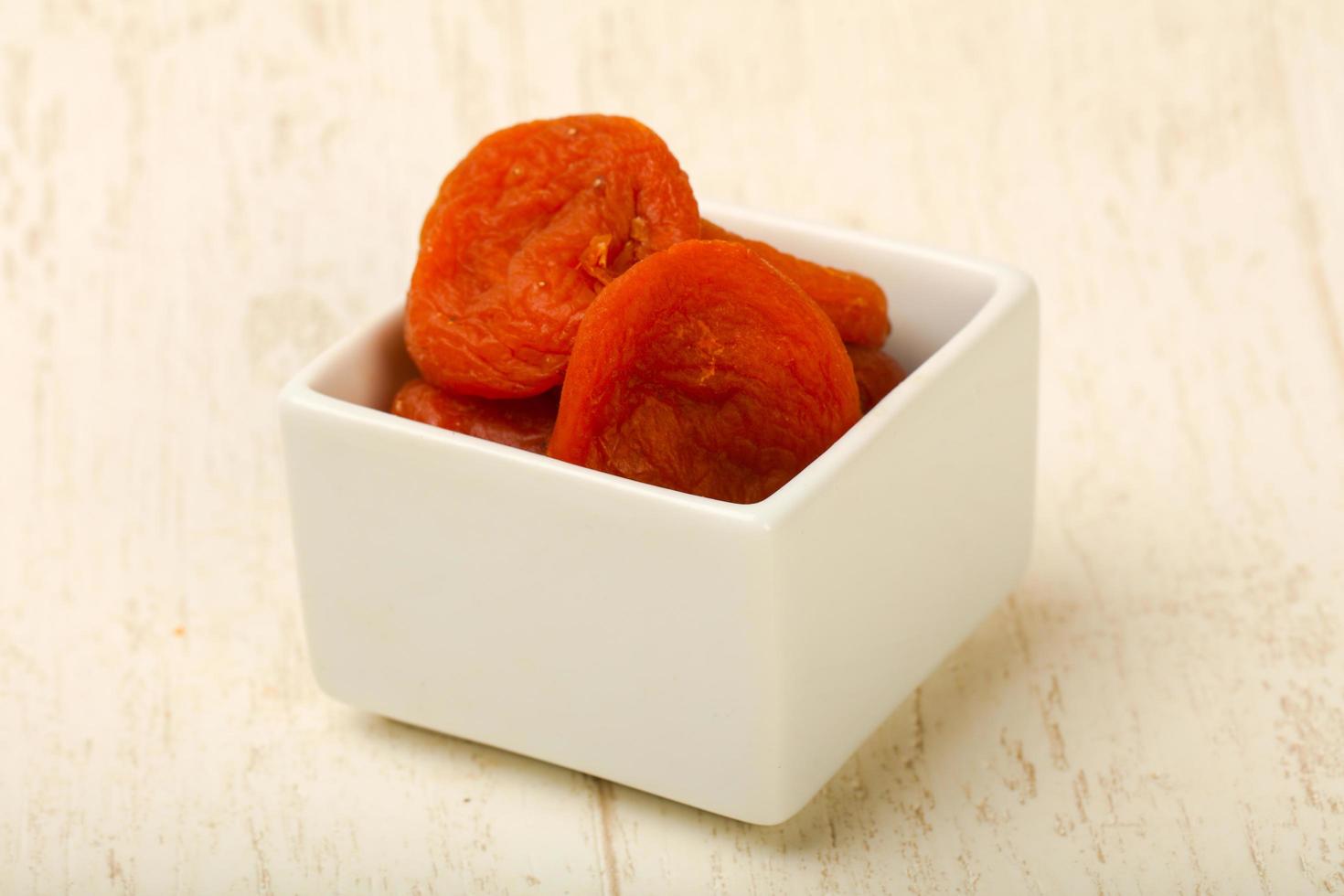 Dry apricot in a bowl on wooden background photo