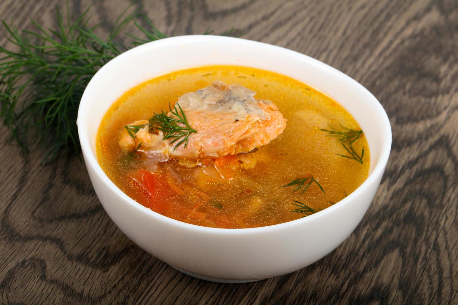 Salmon soup in a bowl on wooden background photo