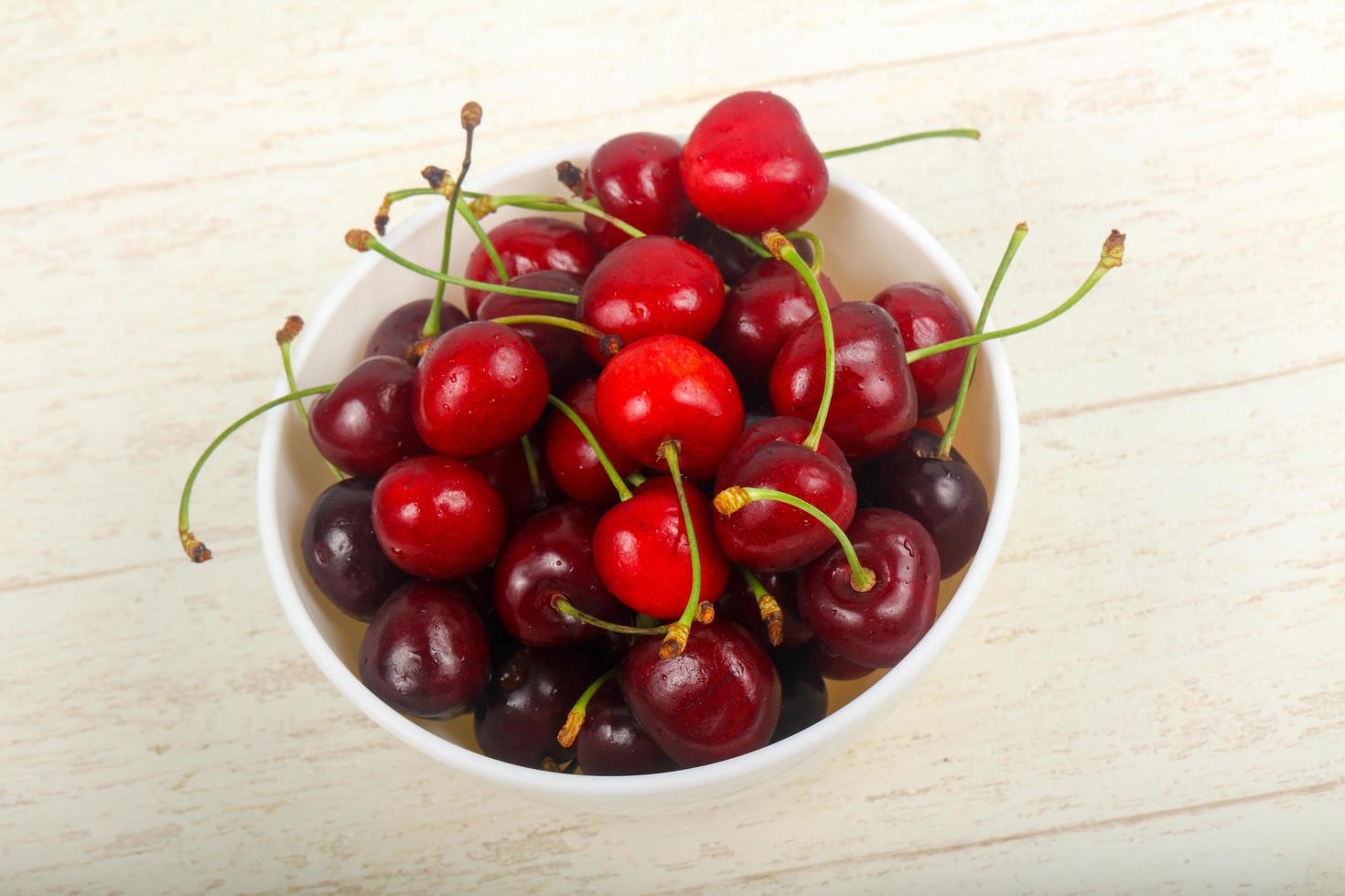 Sweet cherry in a bowl on wooden background photo