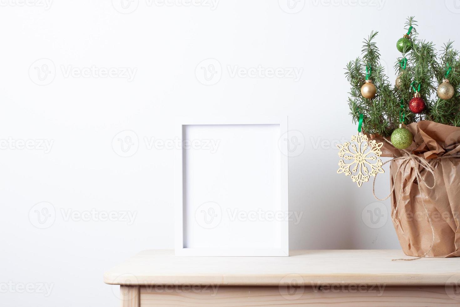 Zero waste Christmas natural decoration with rosemary as alternative Christmas tree and white mock up frame on table. Close up, copy space photo