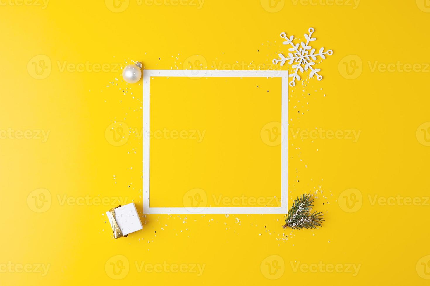 composición mínima navideña con marco blanco y regalo de embalaje sobre fondo amarillo. endecha plana, espacio de copia foto