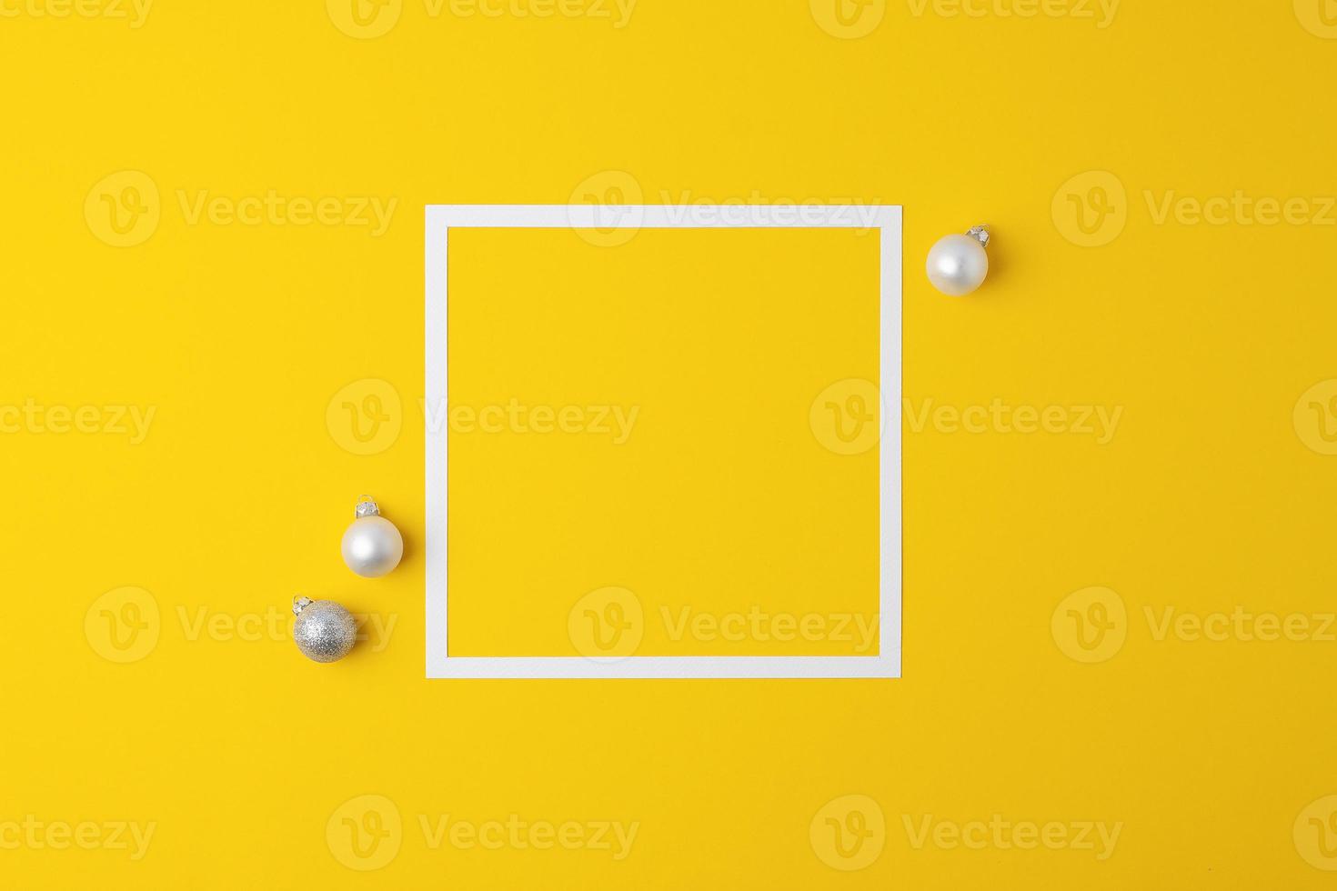 Christmas yellow minimal background with white frame and grey ball. Flat lay, copy space photo