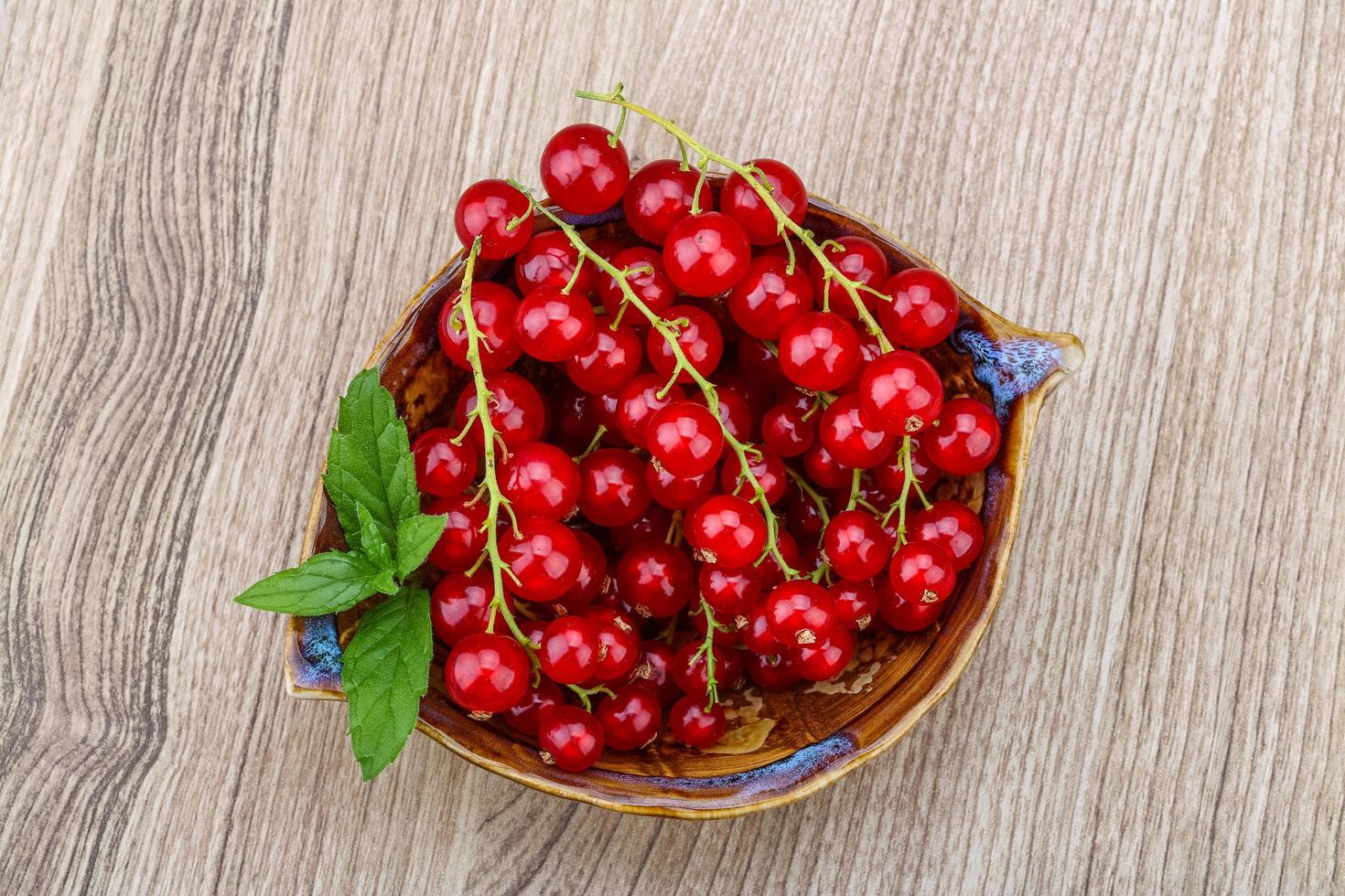 Red currants in a bowl on wooden background photo