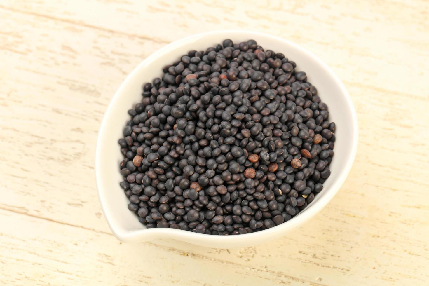 Black lentils in a bowl on wooden background photo