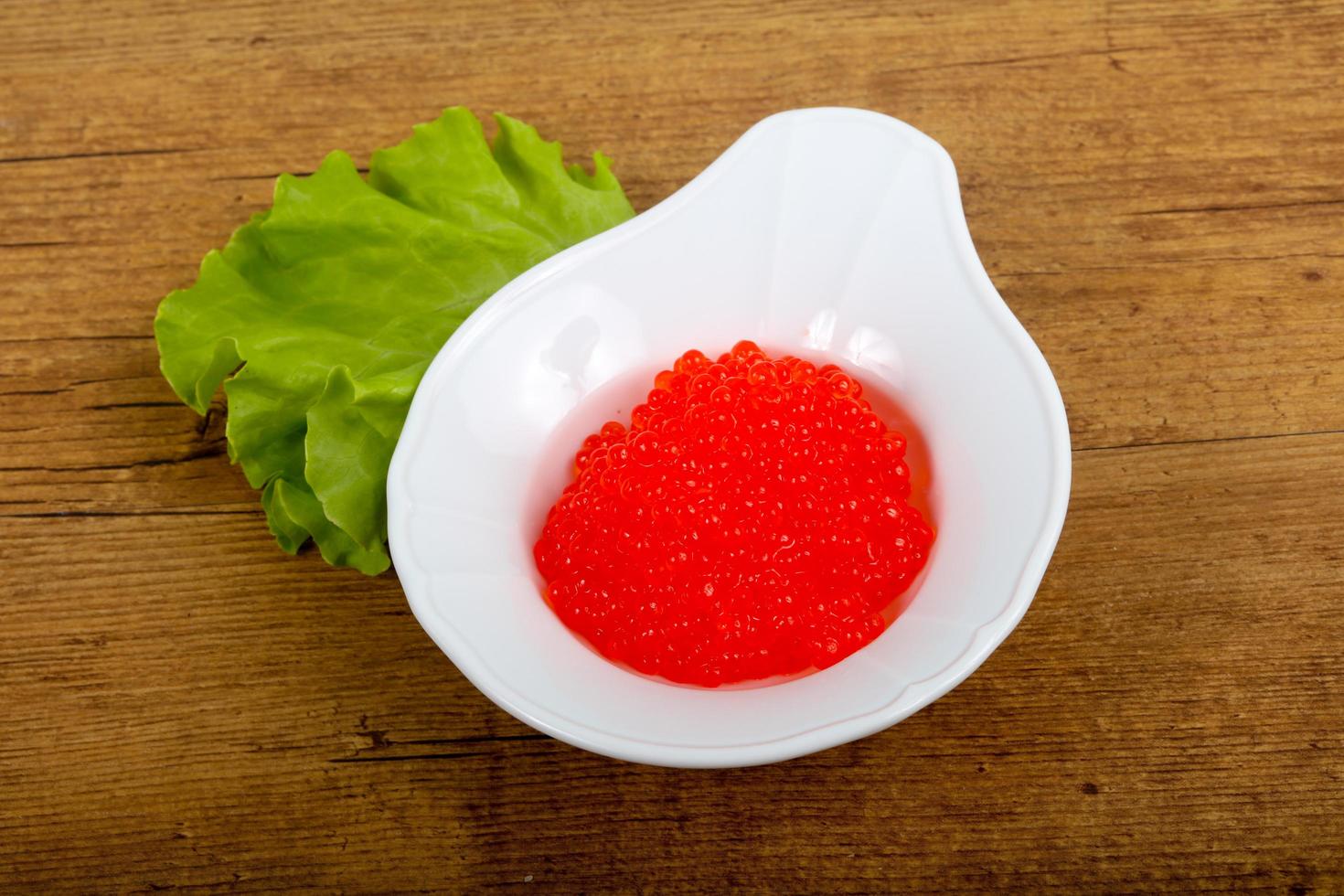 Red caviar on the plate and wooden background photo