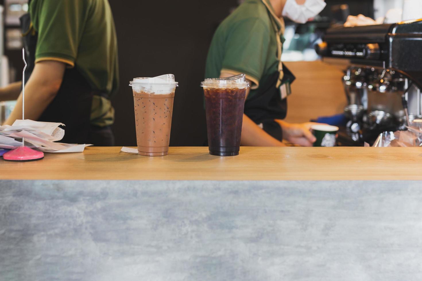 Iced coffee top of counter with barista working in background in cafe. photo