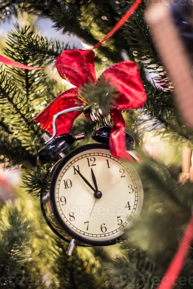 Christmas clock red bow on the branch of a tree photo