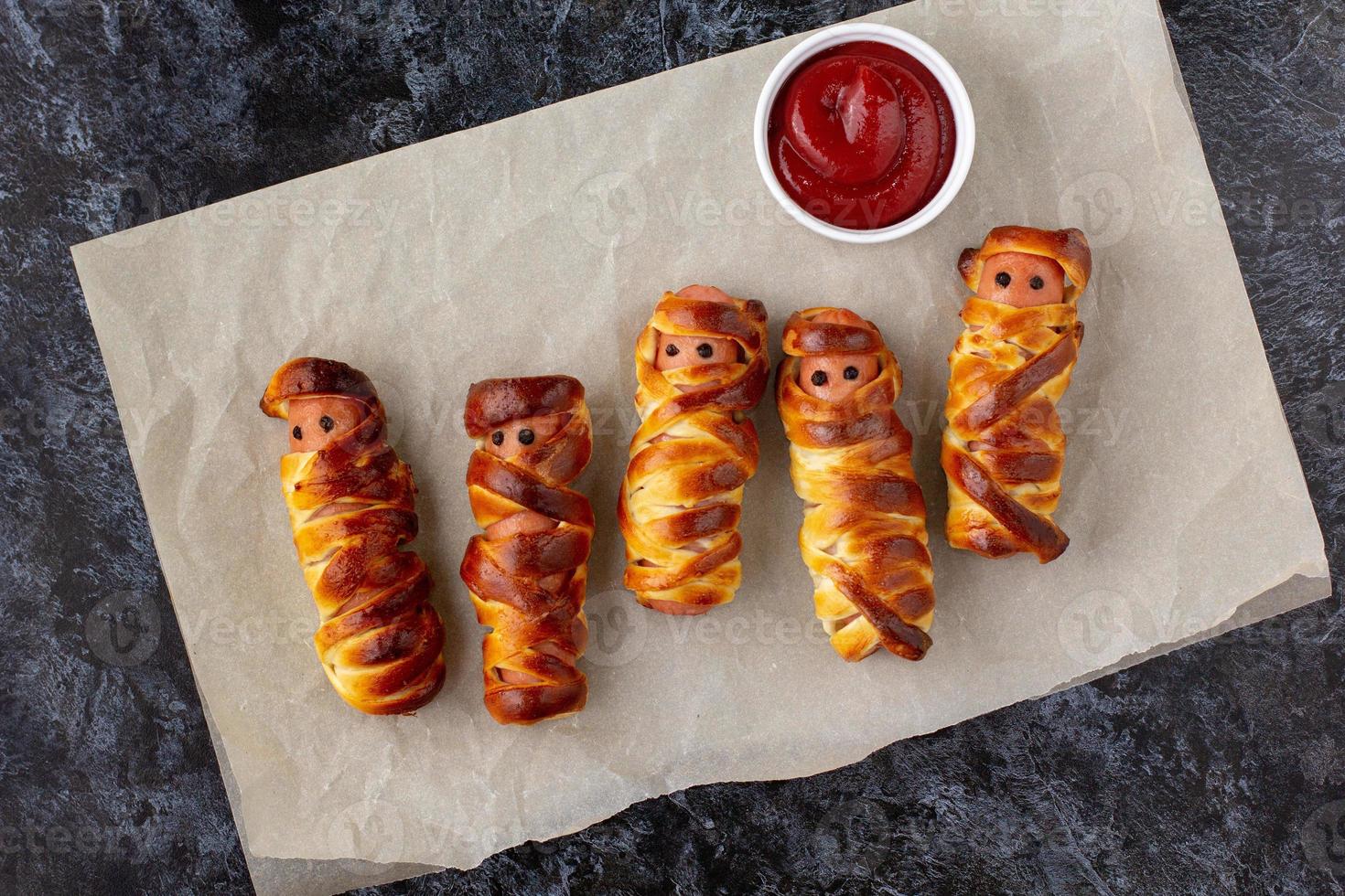 Scary sausage mummies in dough for kids party. Funny crazy Halloween food for children. photo