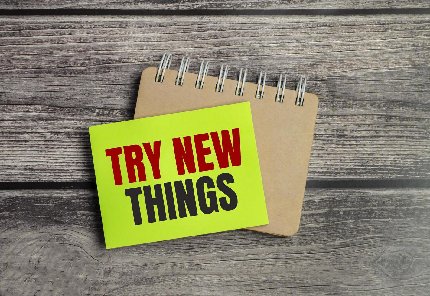 TRY NEW THINGS words on green sticker on wooden background photo