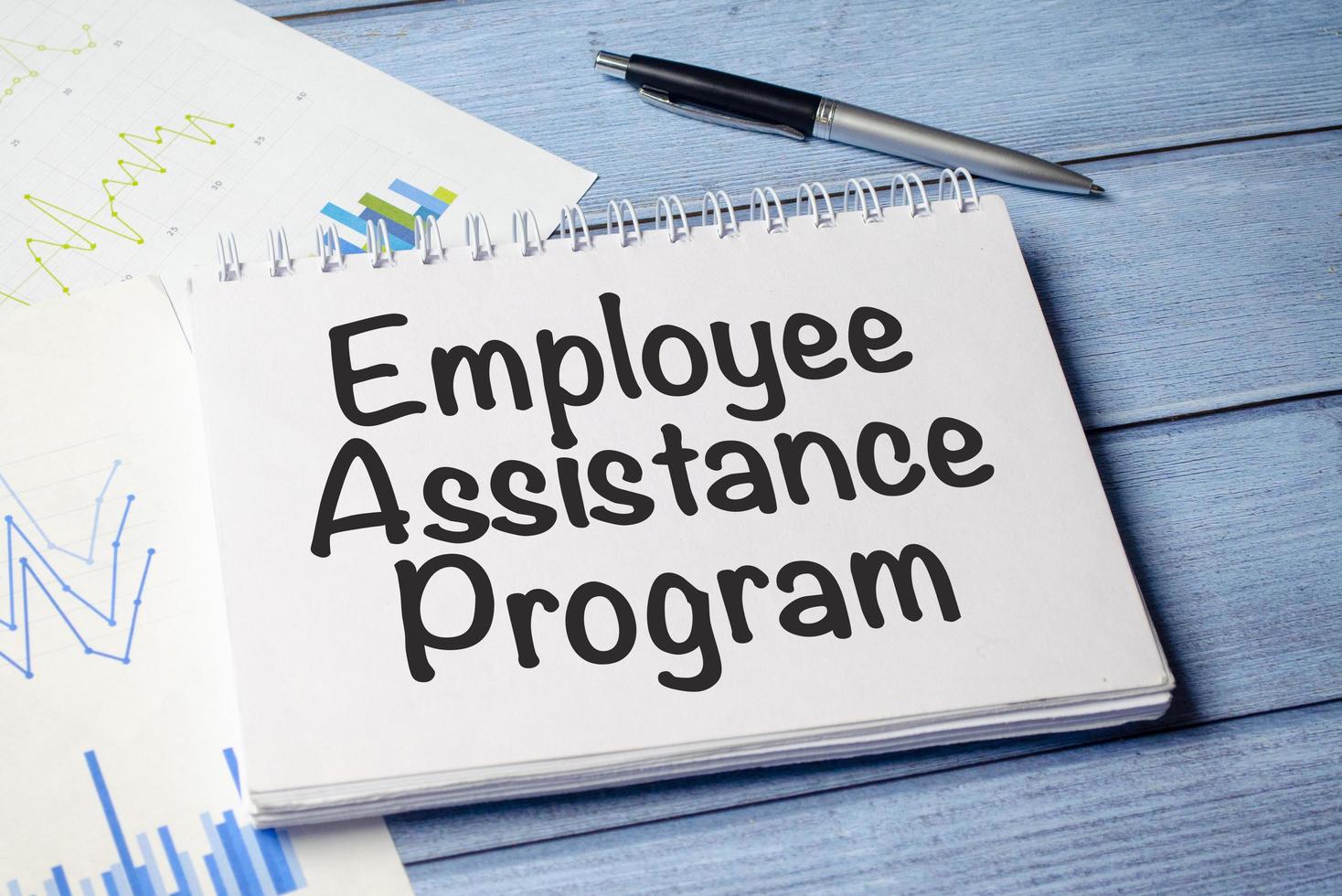 paper with the text EAP Employee Assistance Program on blue wooden background and charts photo