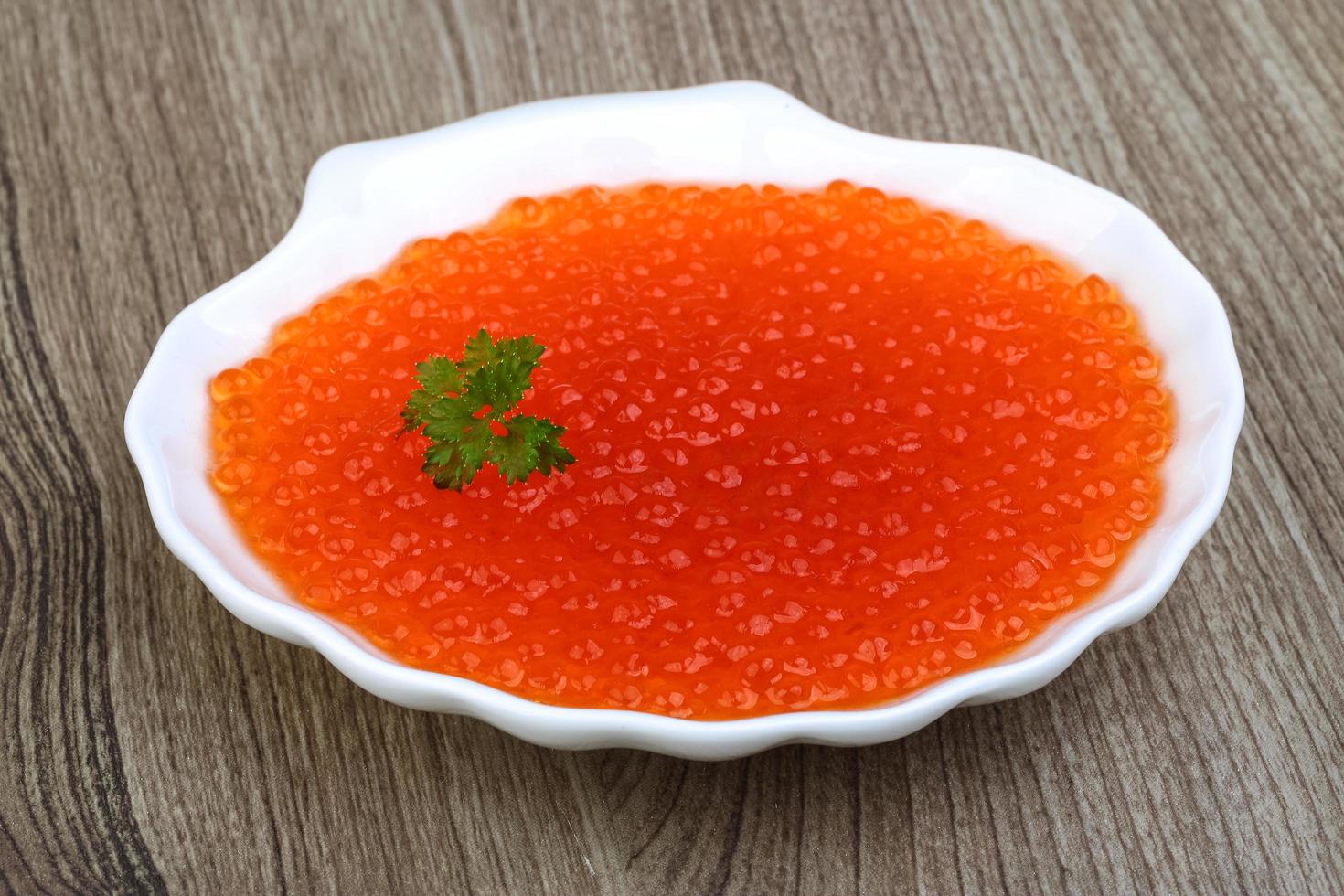 Red caviar in a bowl on wooden background photo