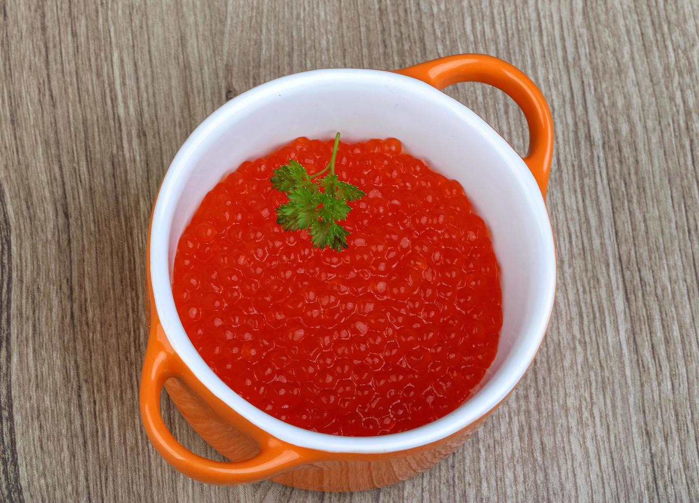 Red caviar in a bowl on wooden background photo