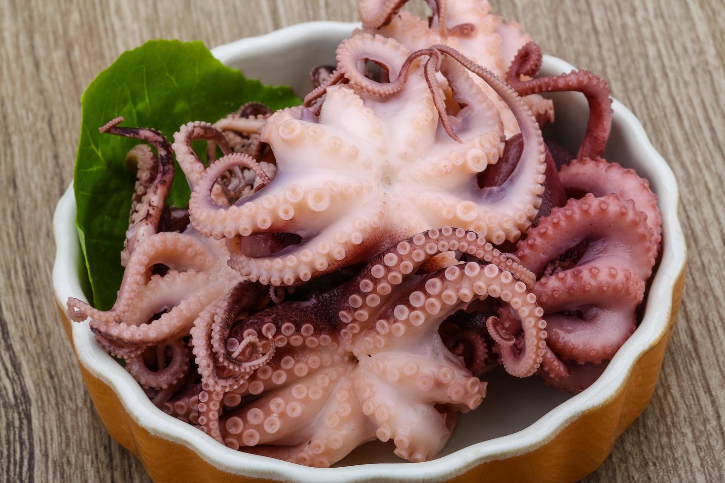 pulpo marinado en un bol sobre fondo de madera foto