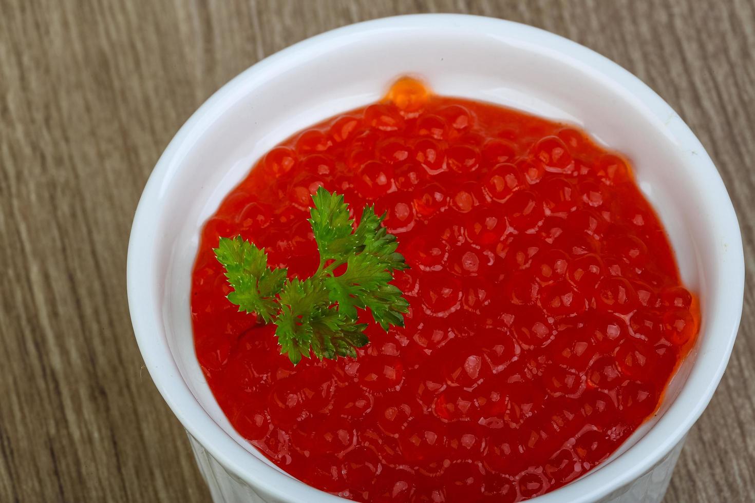 Red caviar in a bowl on wooden background photo