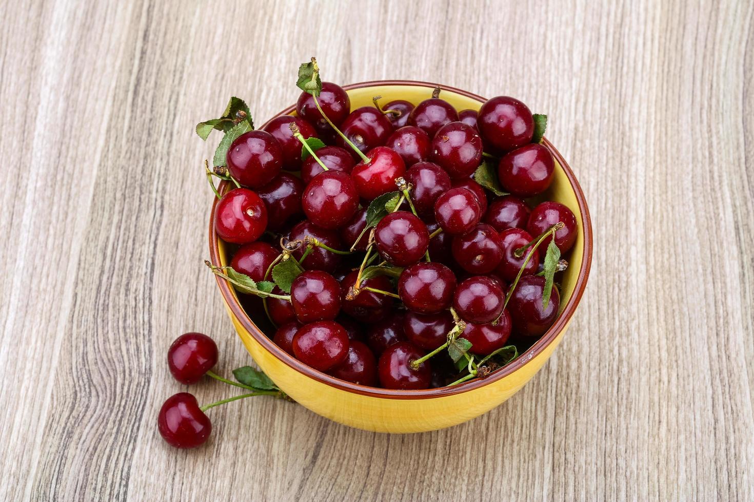 cereza en un recipiente sobre fondo de madera foto