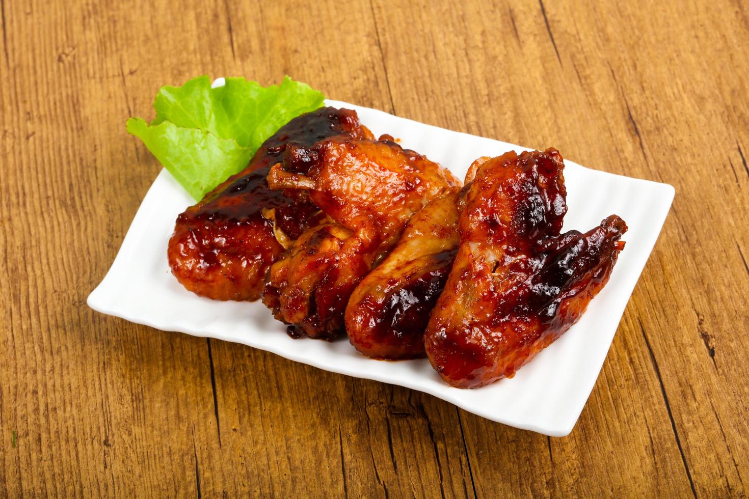 Chicken wings on the plate and wooden background photo