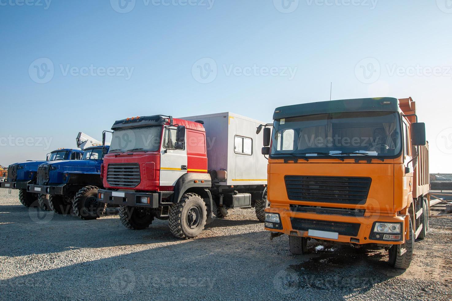 A row of large dump trucks and machines at a construction site photo