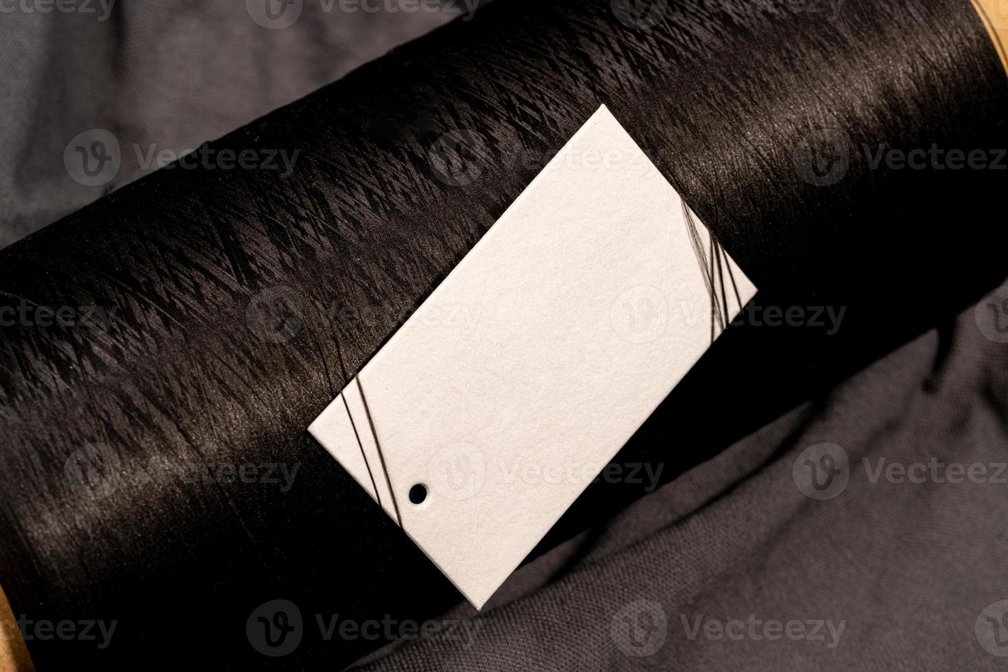 A closeup shot of a blank white clothing tag on a roll of black string photo