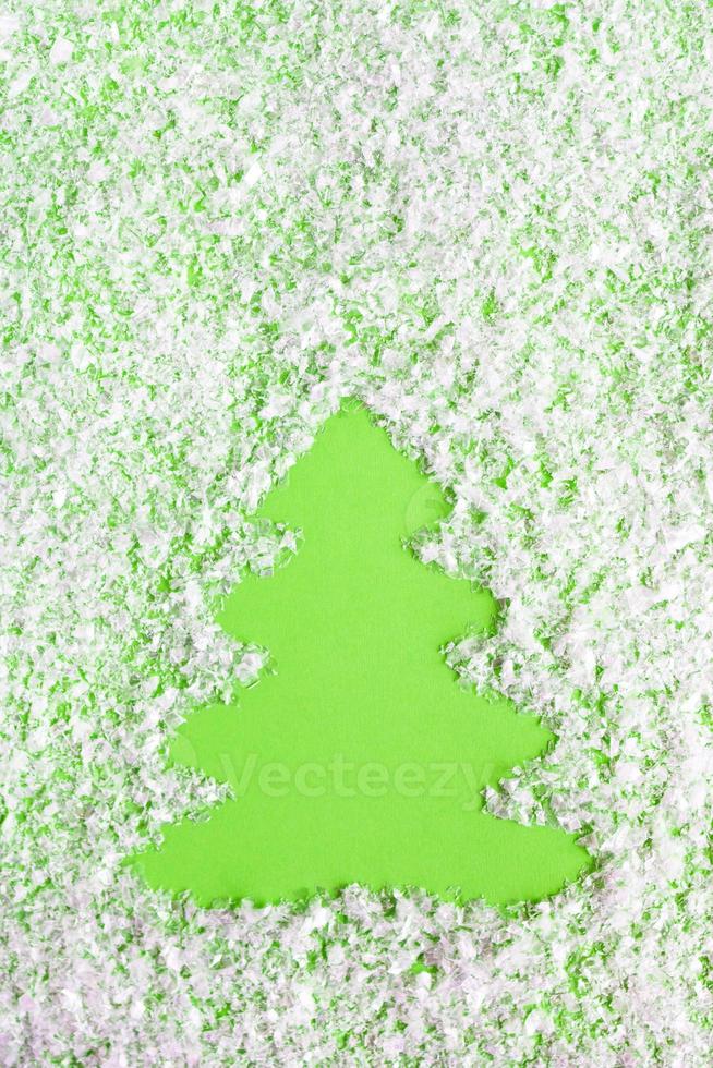 composición de invierno con árbol de navidad sobre un fondo verde con nieve artificial, puesta plana. tarjeta de felicitación para año nuevo con espacio de copia. foto
