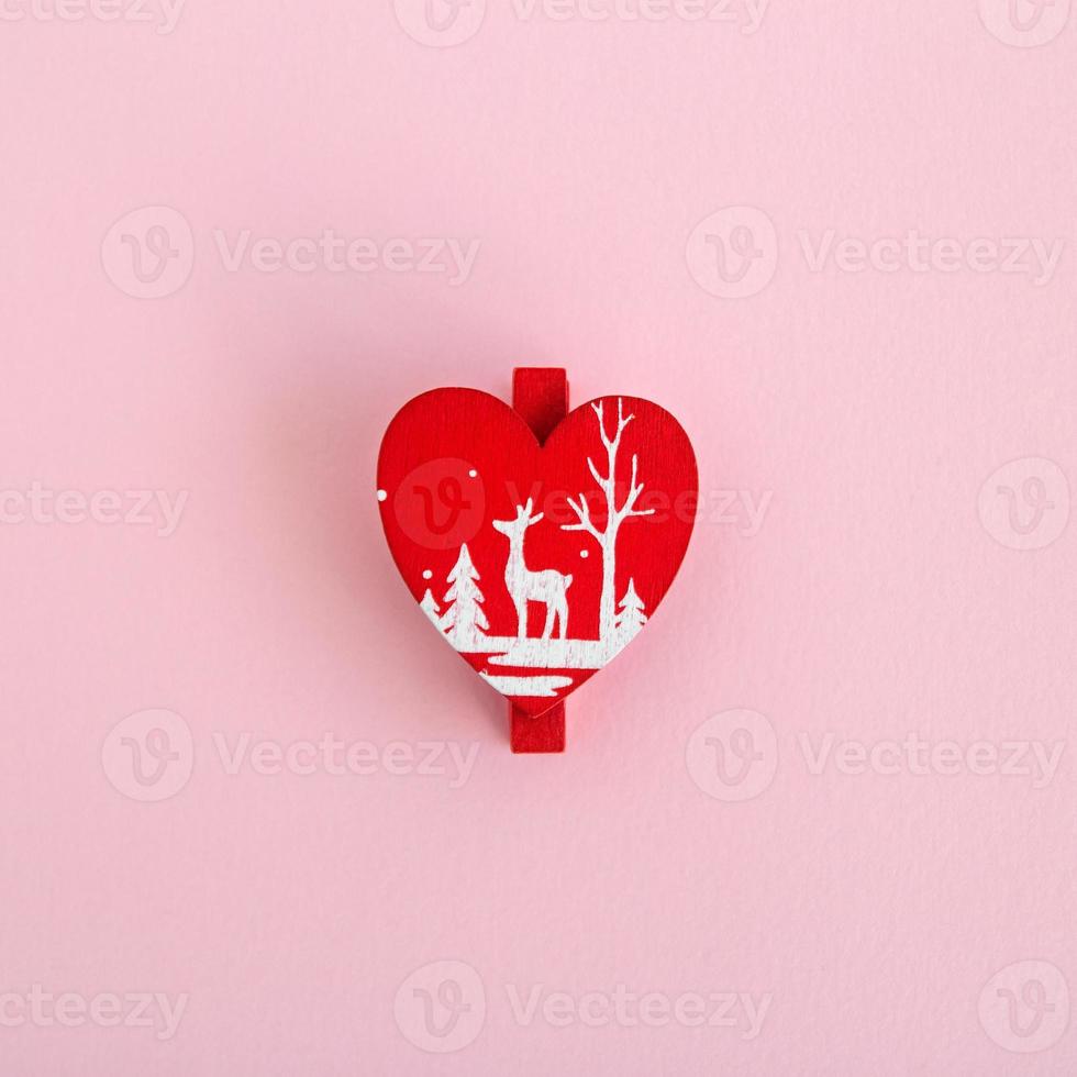 Red wooden Christmas and New Year decoration in the form of heart on a pink background, top view. photo