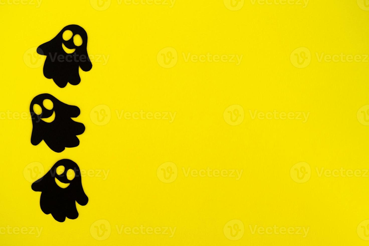 decoraciones navideñas para halloween. tres fantasmas de papel negro sobre un fondo amarillo, vista superior. foto