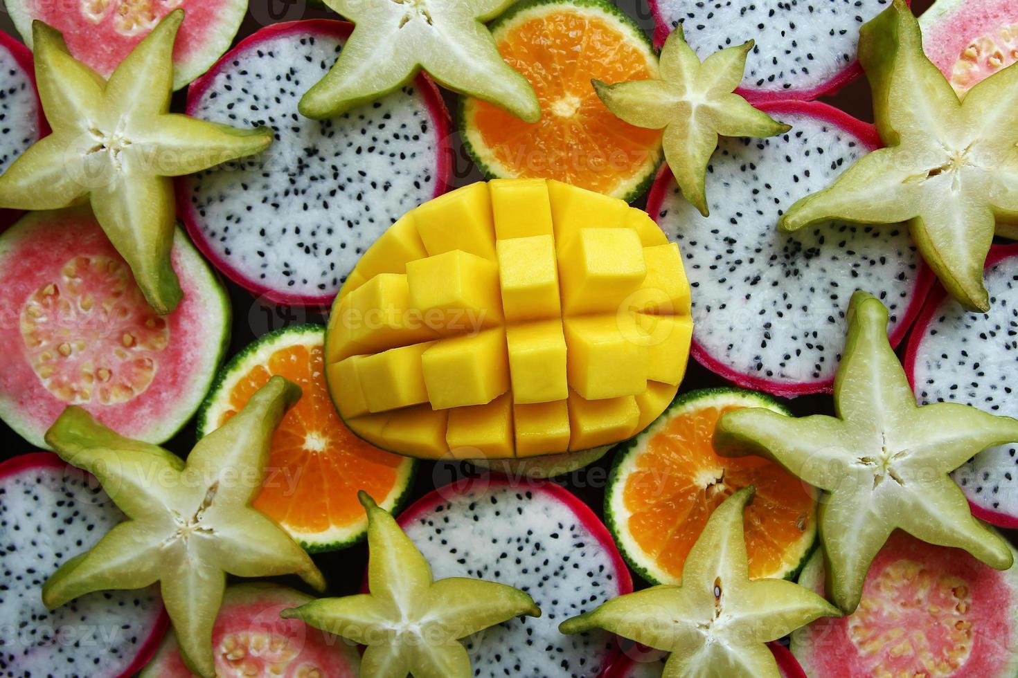 Top view on the mixed fresh and ripe tropical fruits - mango, tangerine, guava, dragon fruit, star fruit, sapodilla photo