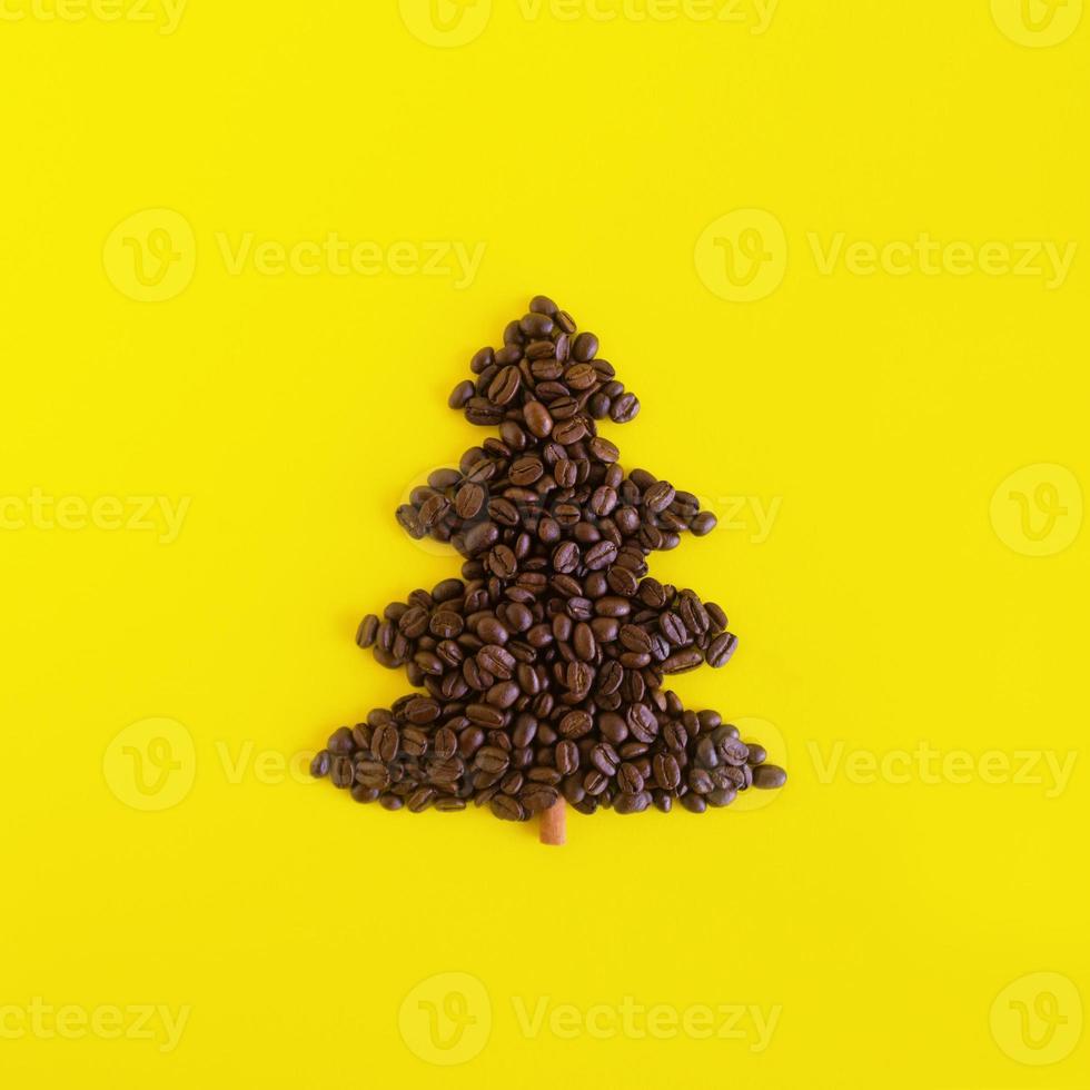 composición invernal con árbol de navidad hecho con granos de café y palo de canela decorado sobre un fondo amarillo, plano. tarjeta de felicitación para año nuevo con espacio de copia. foto